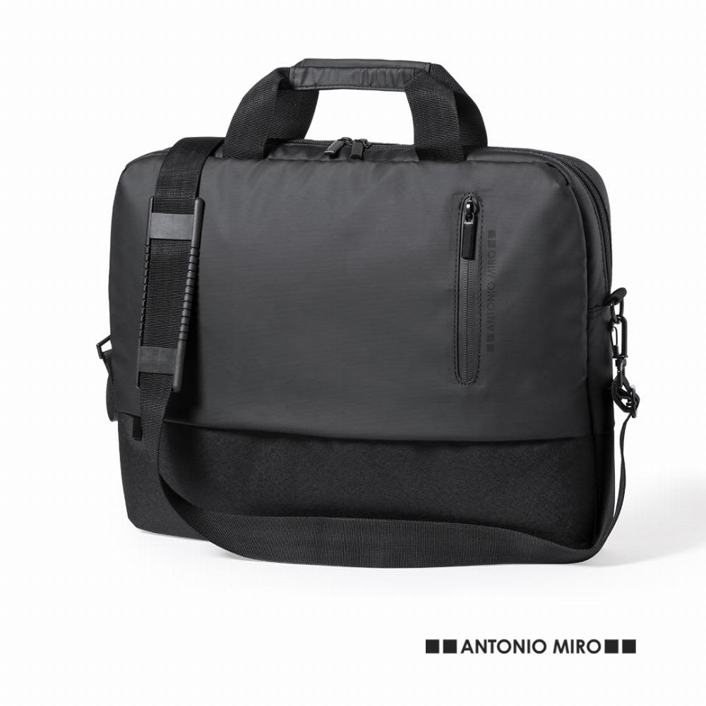 A black laptop bag with a handle, removable shoulder strap, and zippered pockets. It has a logo on the front. Mitchel - Image 1