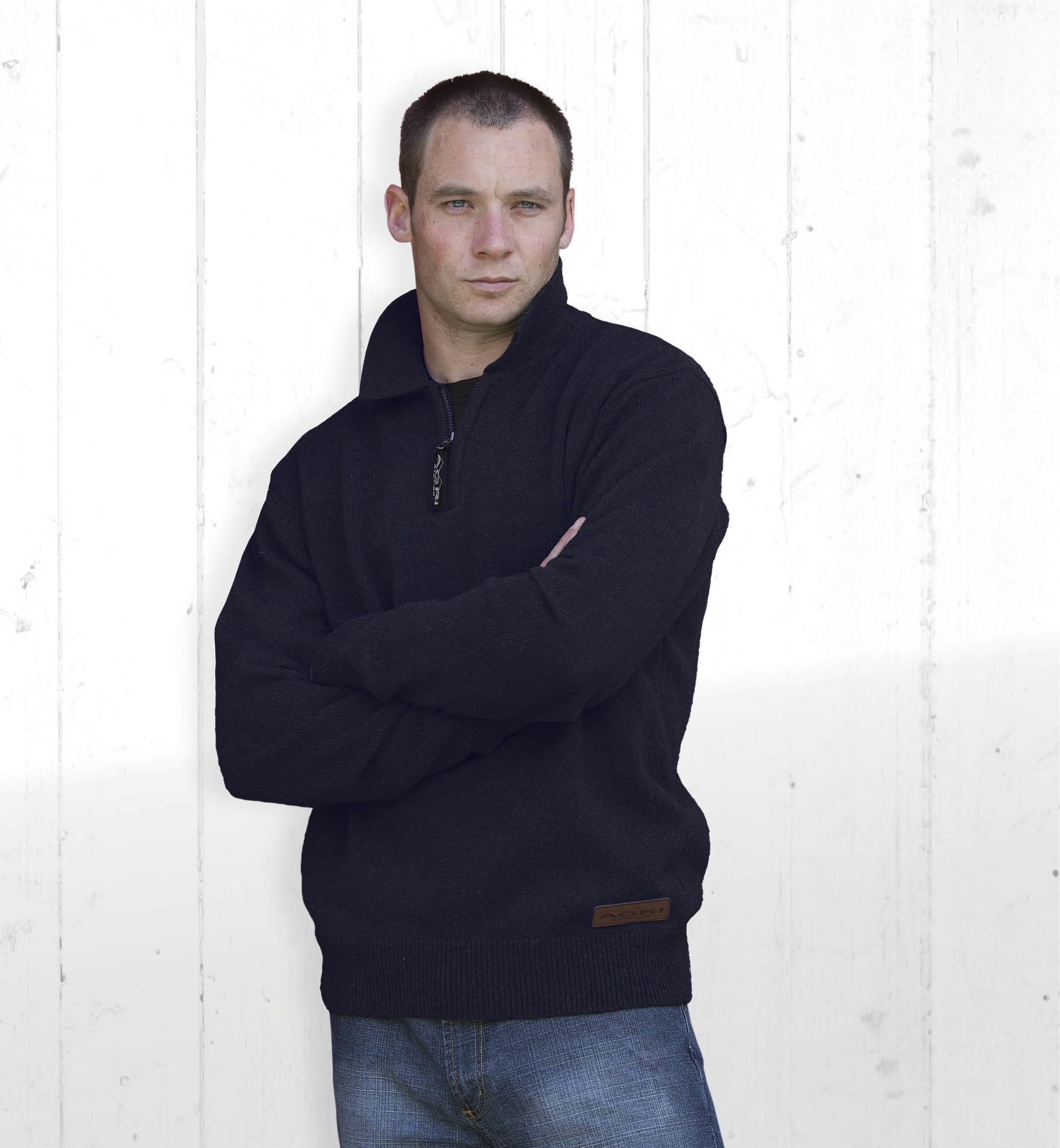 A black Agri Station Boundary Jersey with a half-zip collar, worn by a model against a textured white background. Agri Station Boundary Jersey - Image 1