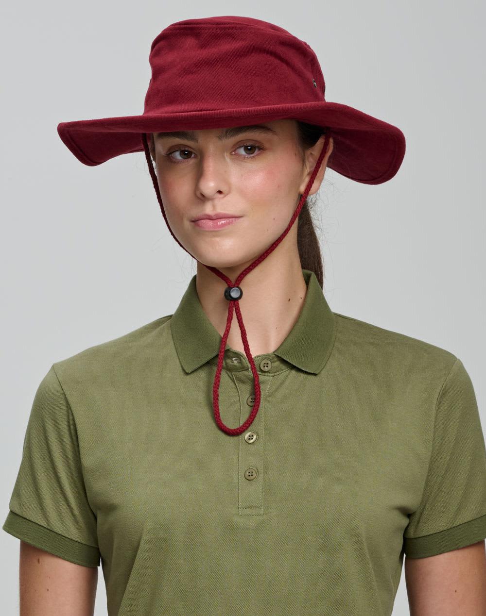 A beige bucket hat with a chin strap and a branded logo, featuring a wide brim for sun protection. Surf Hat - Image 1