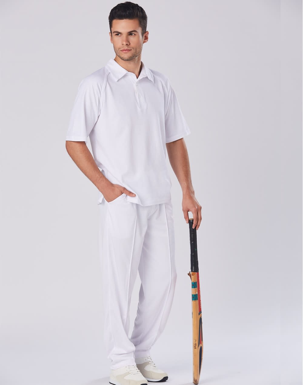 A model wearing white men's cricket pants, paired with a matching polo shirt, holding a cricket bat. Mens cricket pants - Image 1