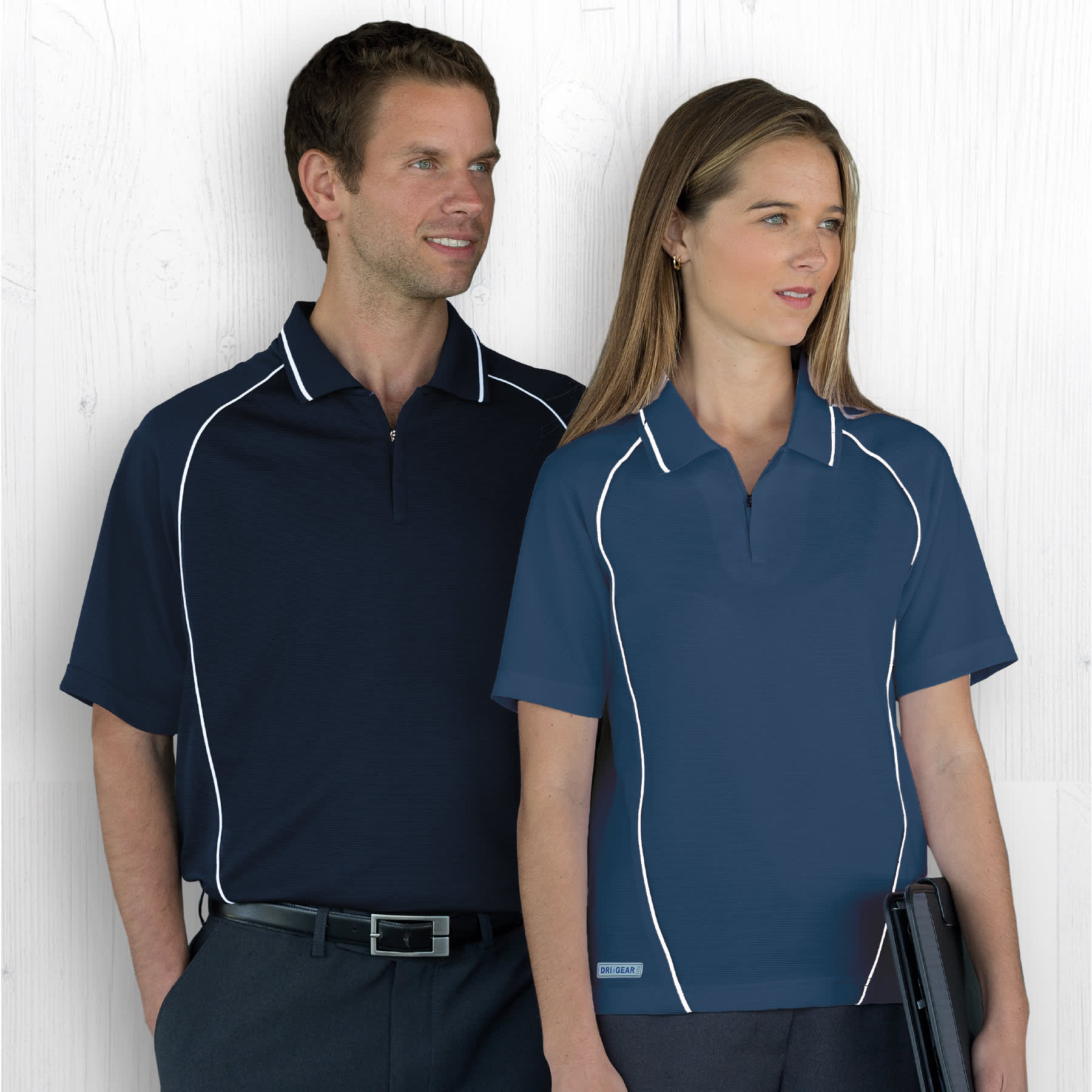 A navy polo shirt with white piping, displayed on a male and female model, featuring a logo. Dri Gear Piped Ottoman Instinct Polo - Image 1