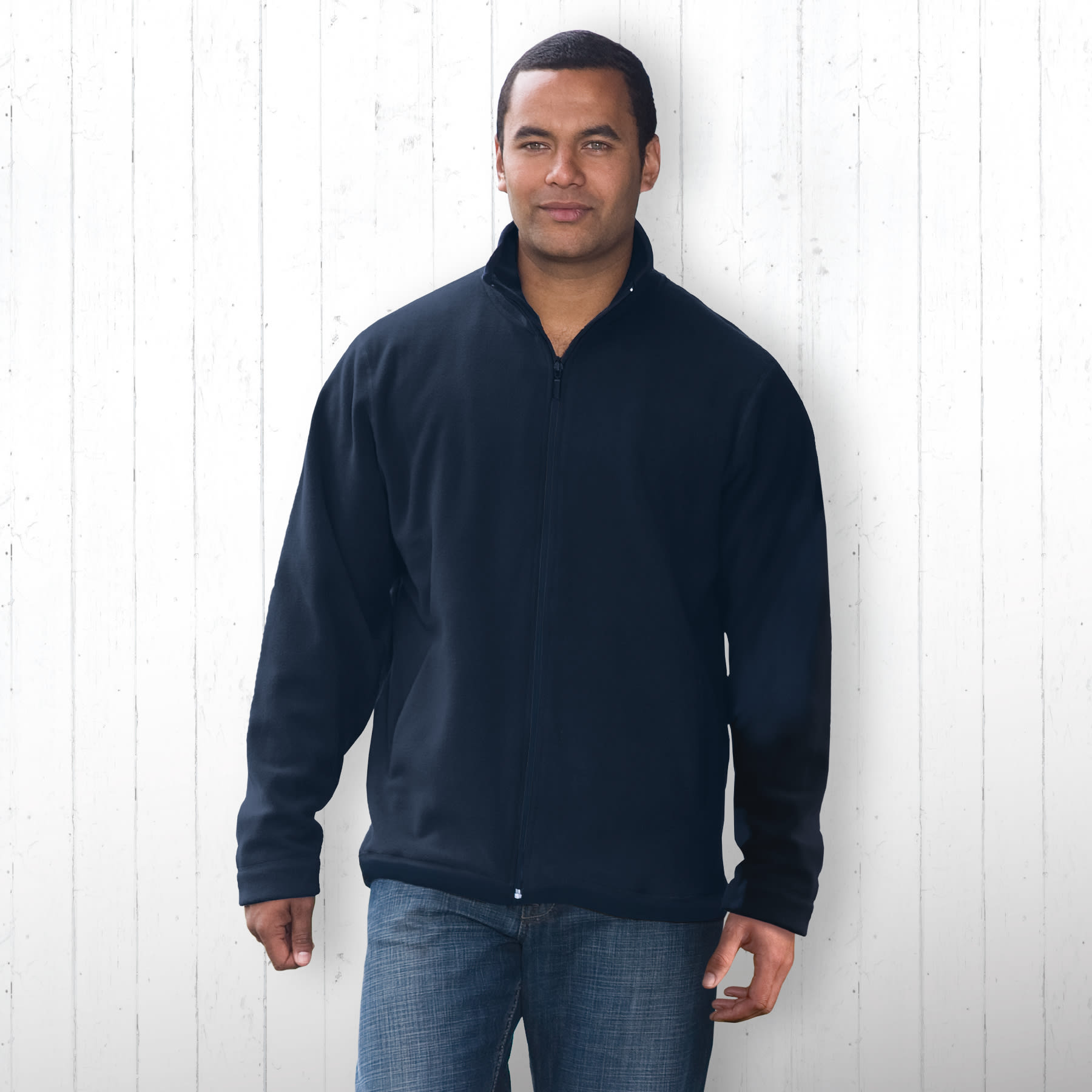 A man wearing a navy polar fleece jacket, featuring a zip front and a casual fit, stands against a white wooden backdrop. Ice Vista Jacket - Mens - Image 1