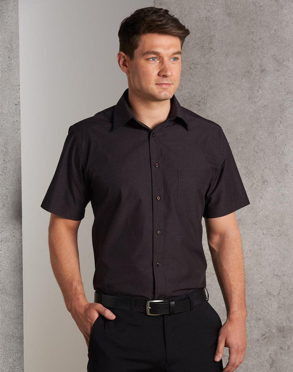 A short sleeve button-up shirt in dark brown, featuring a chest pocket and a collar, worn by a model. Men's Nano Tech Short Sleeve Shirt - Image 1