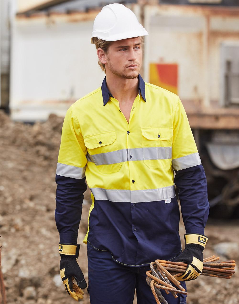 A high-visibility cotton drill shirt in yellow and navy with reflective stripes, worn by a model on a construction site. Hi-Vs cotton drill shirt 3M tape - Image 1