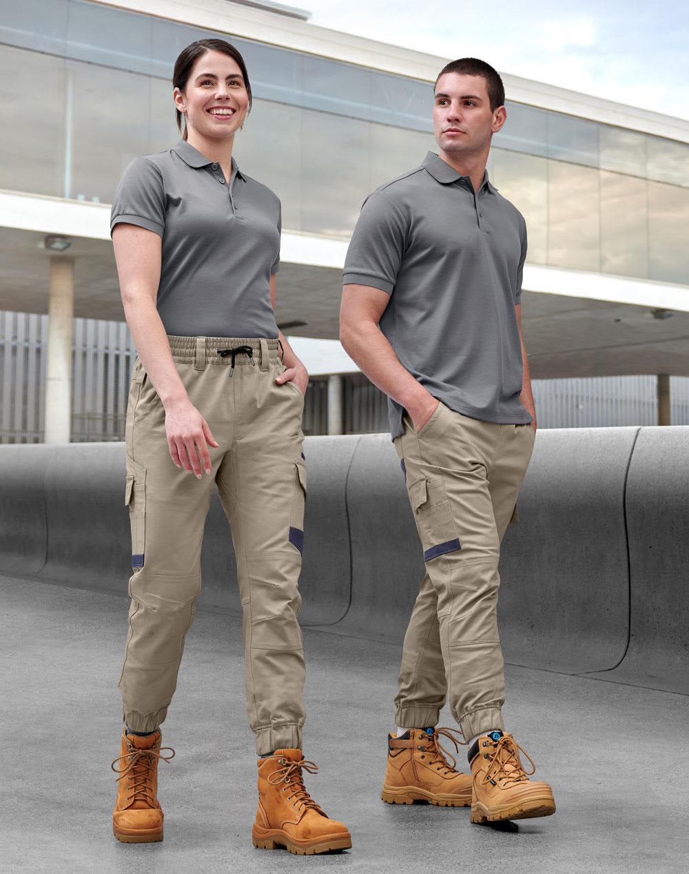 Unisex cotton stretch drill cuffed work pants in khaki, modelled by two people wearing grey tops and work boots. Unisex Cotton Stretch Drill Cuffed Work Pants - Image 1