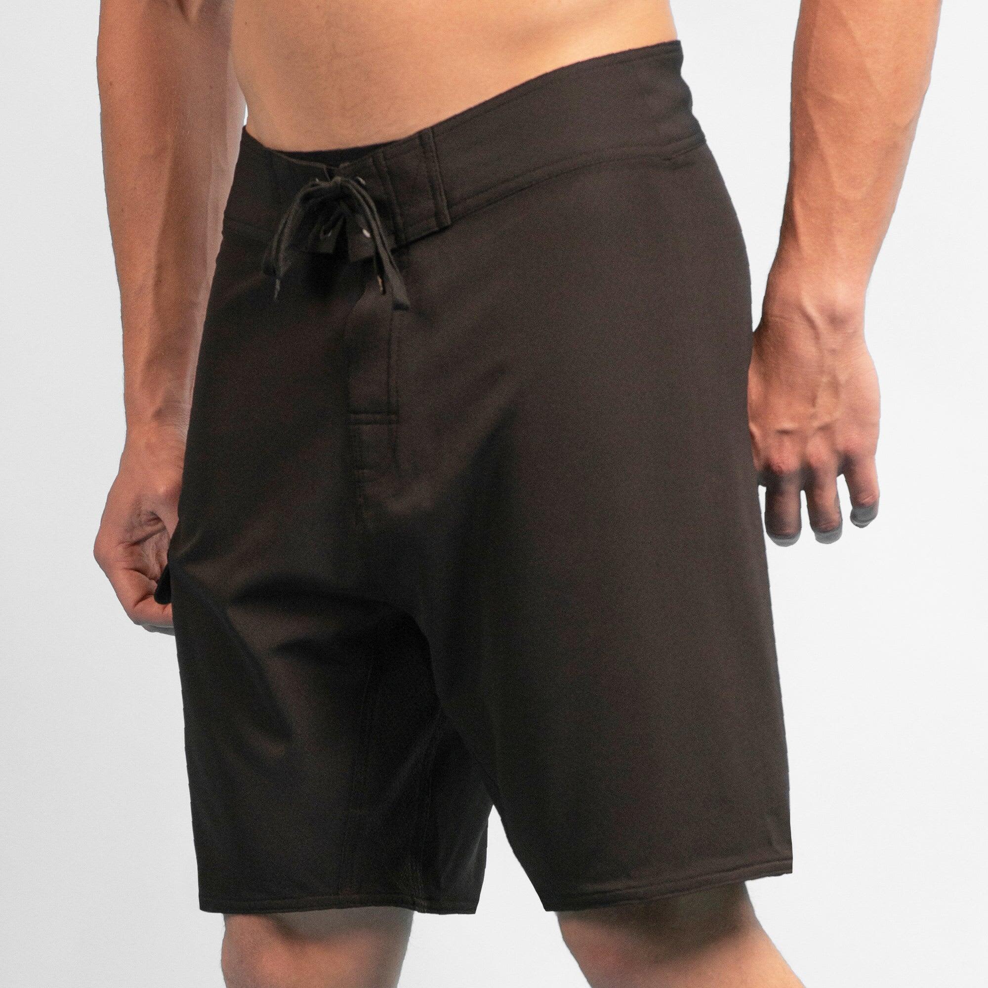 Black 4-way stretch dobby boardshorts with a drawstring waistband, featuring a logo on the side. 4-Way Stretch Dobbie Boardshorts - Image 1