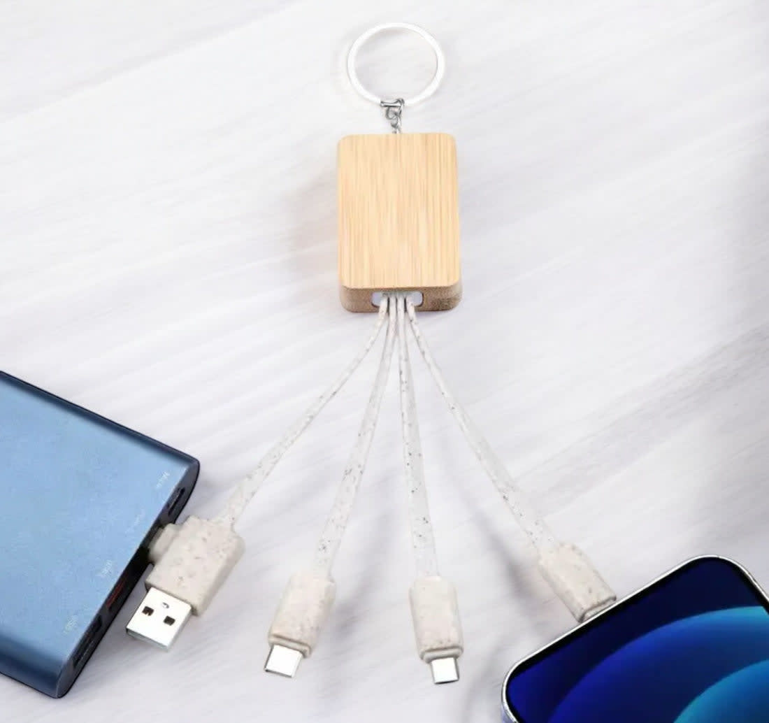 A bamboo multi charger cable with multiple connectors, attached to a keyring, and surrounded by a smartphone and power bank. Block Sustainable Multi Charger Cable - Image 1