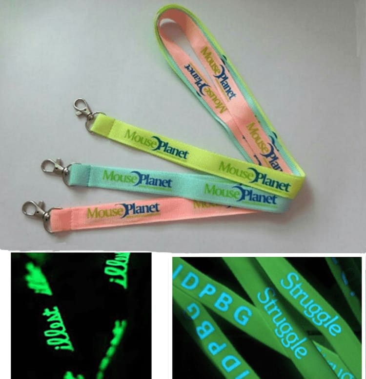 A set of glow-in-the-dark lanyards in pastel green and pink, featuring a logo and light-up text patterns. Glow in Dark Lanyard - Image 1