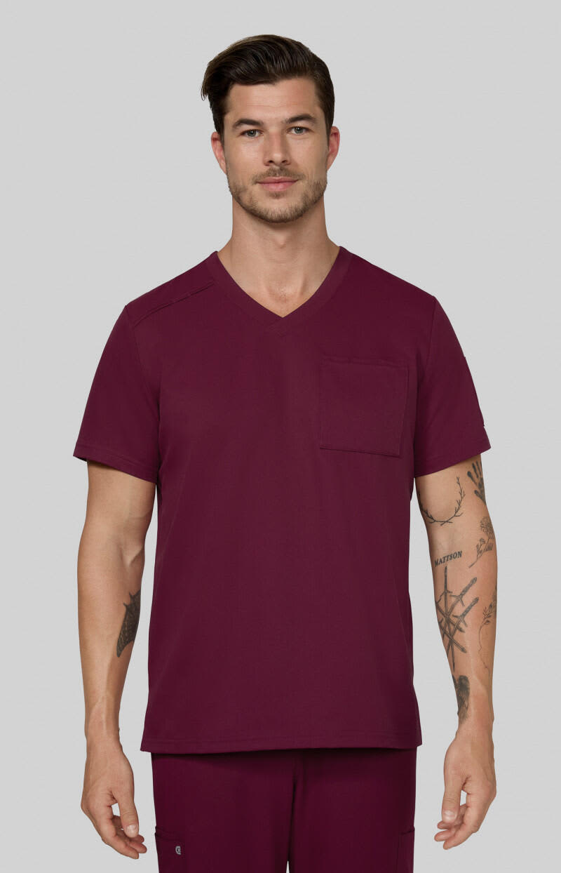 A scrub top in a rich burgundy colour, featuring a V-neck design and a chest pocket, worn by a male model. Arthro Top - Image 1