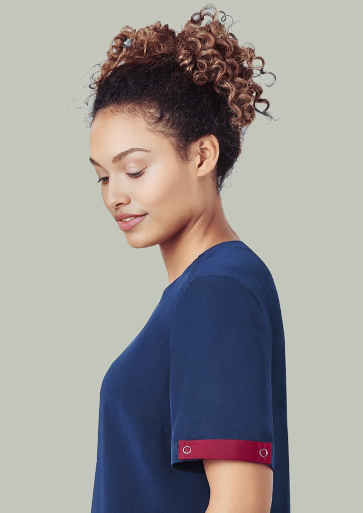 A navy scrub top with a burgundy accent on the sleeve, worn by a woman with curly hair. Unisex Avery Scrub Identifier - Image 1