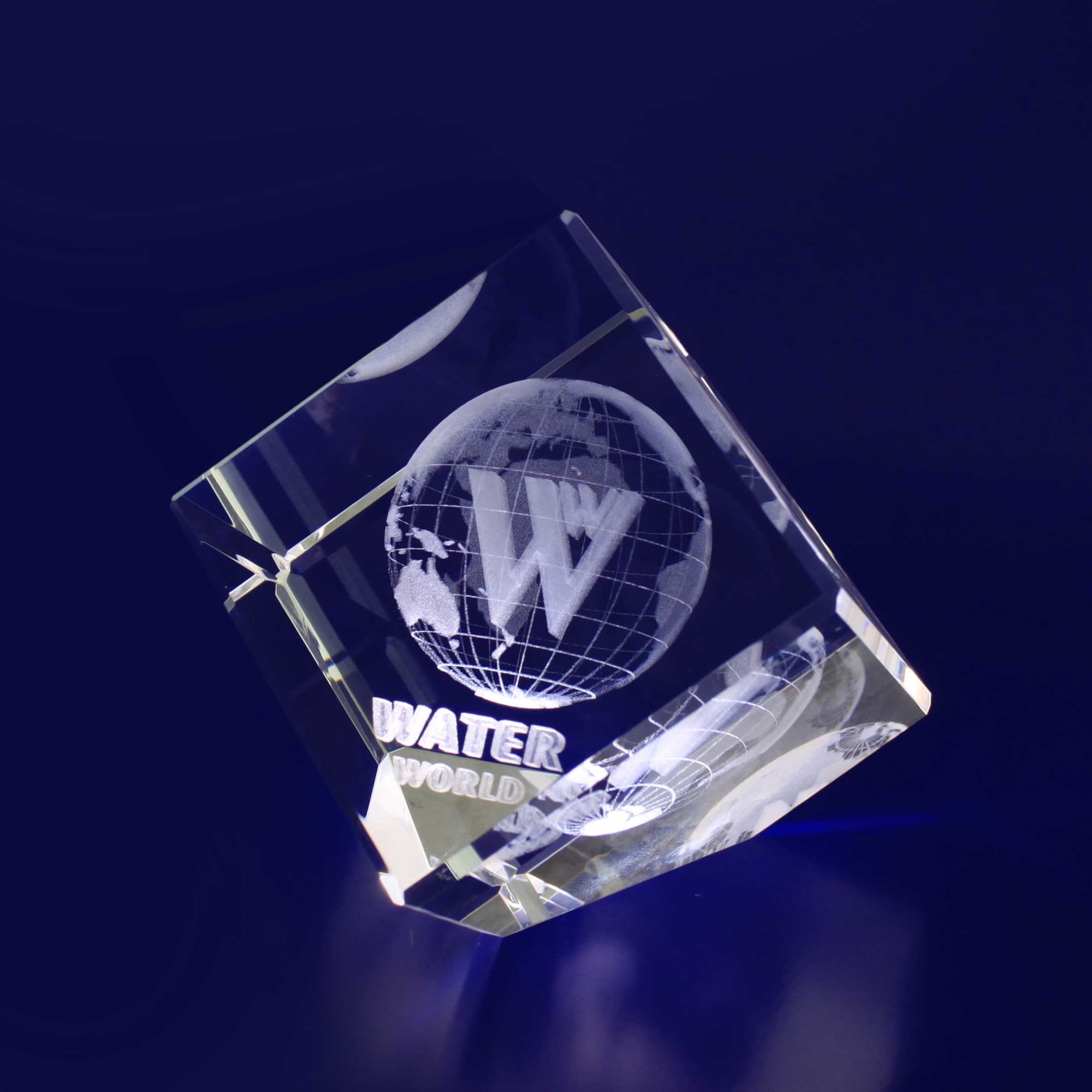 A clear crystal diamond with a globe design and a logo, resting on a dark blue background. 3D Crystal Diamond (60mm) - Image 1