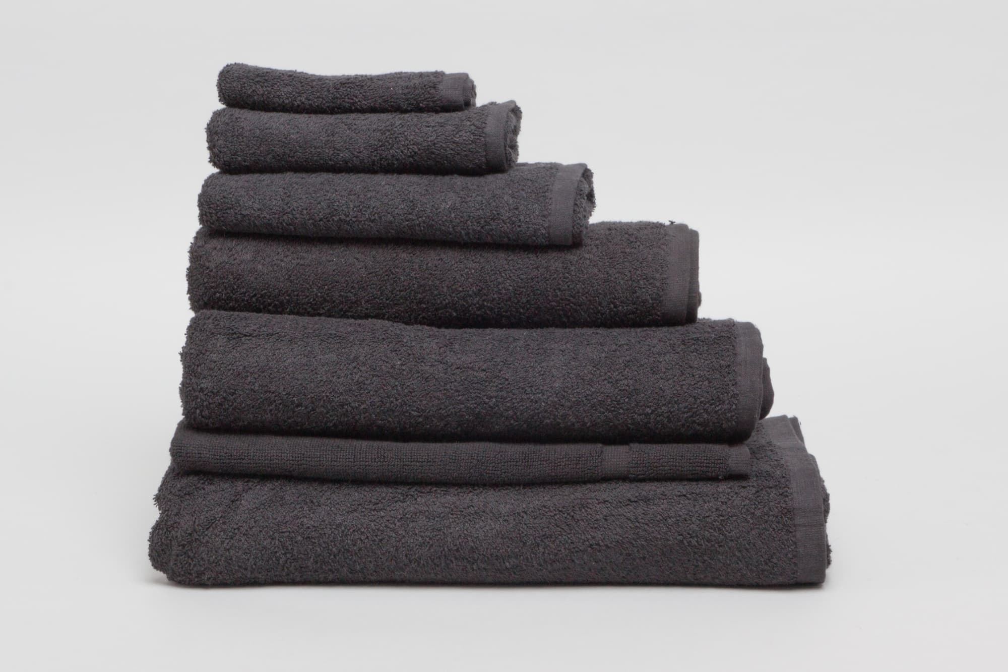 A stack of black towels in various sizes, made from 500 gsm material, featuring a textured finish. Elite Large Hand Towel 500 gsm Black - Image 1