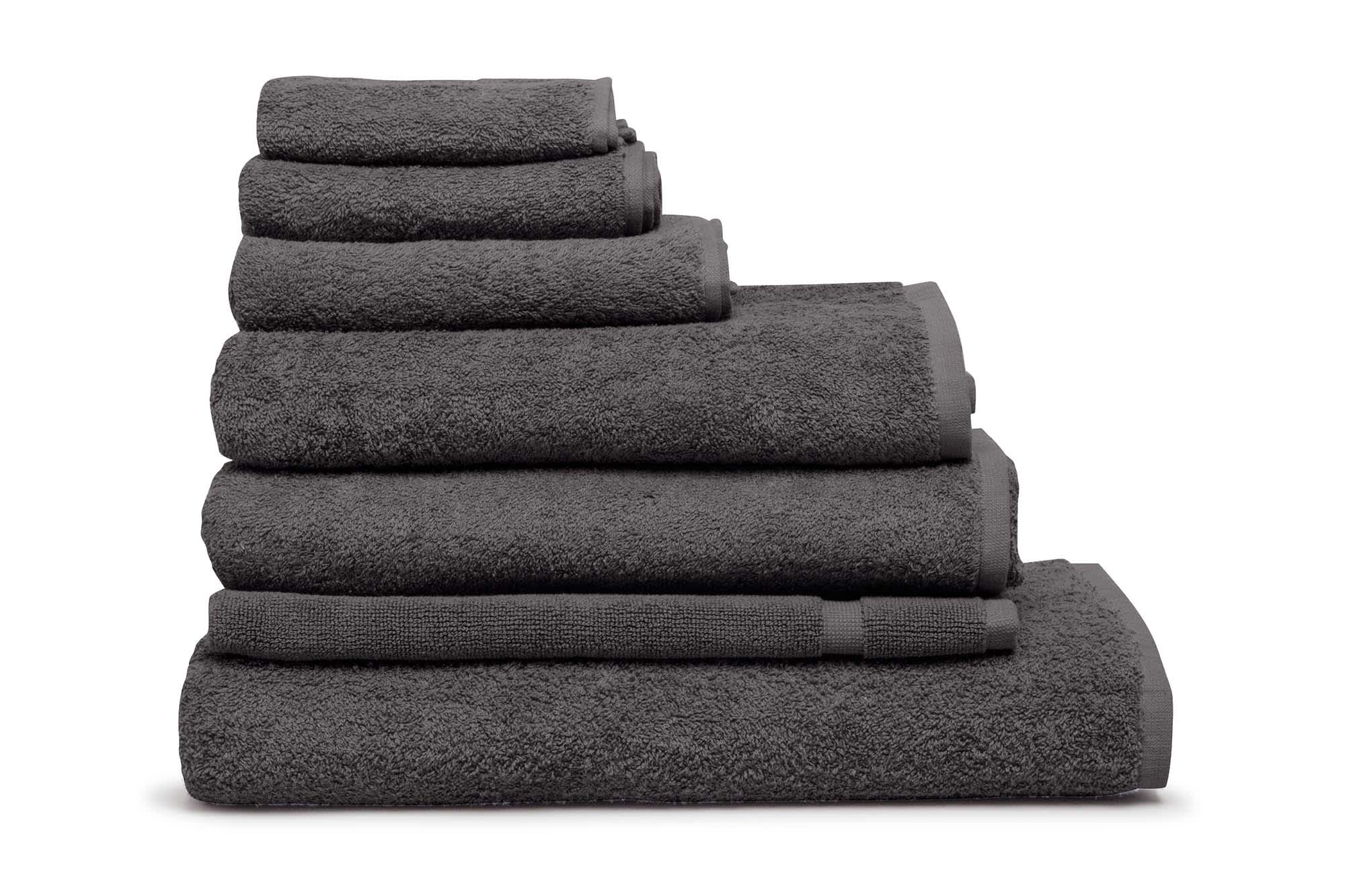 A stack of grey towels in various sizes, showcasing a plush texture and a simple design. The image includes branding. Elite Small Hand Towel 500 gsm Coal - Image 1