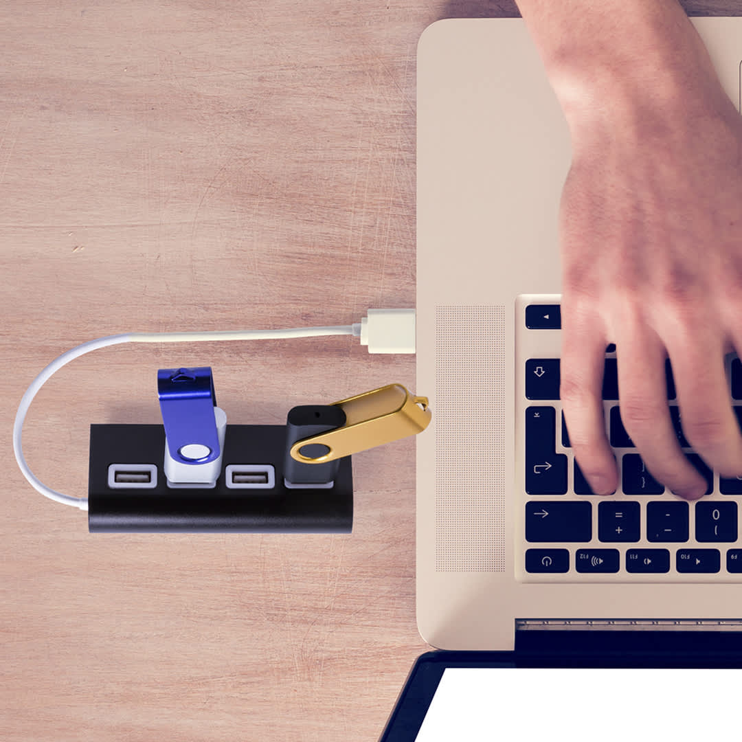 A USB hub with multiple ports in black, with blue and gold USB drives attached, next to a laptop. Weeper - Image 1