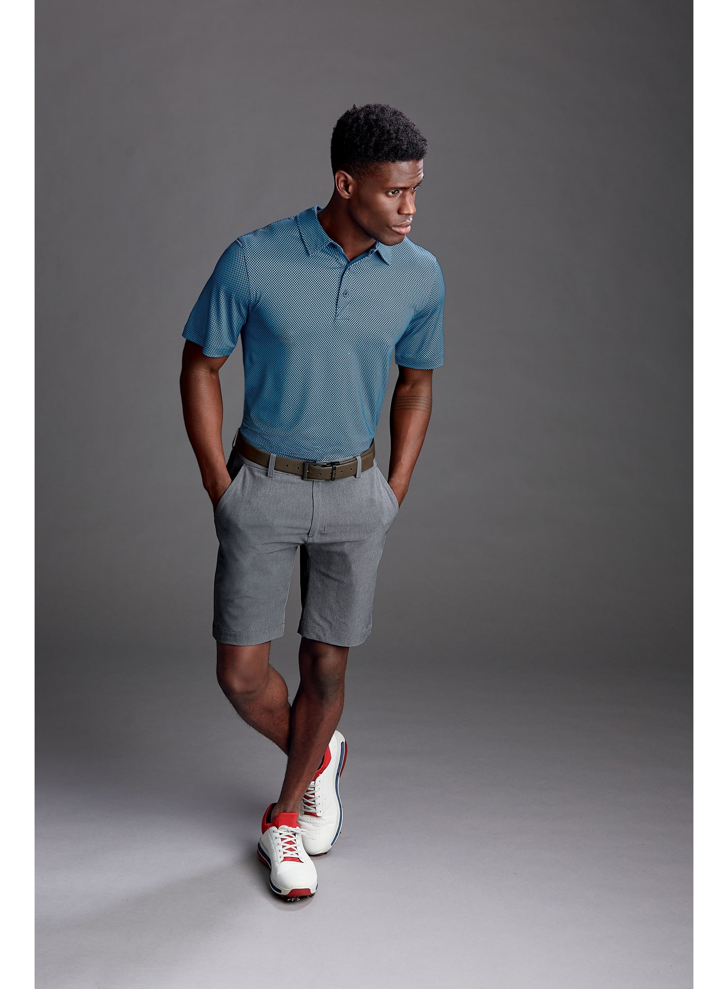 A pair of grey sports shorts, styled with a blue polo shirt and white sneakers, featuring a logo on the shorts. CB DryTec Bainbridge Sport Short - Image 1