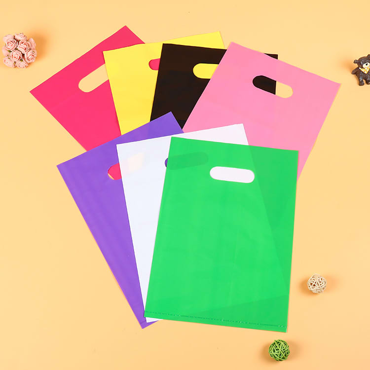 A collection of die cut plastic handle bags in pink, yellow, green, white, purple, black, and red, featuring various logos. Die Cut Plastic Handle Bag - Image 1