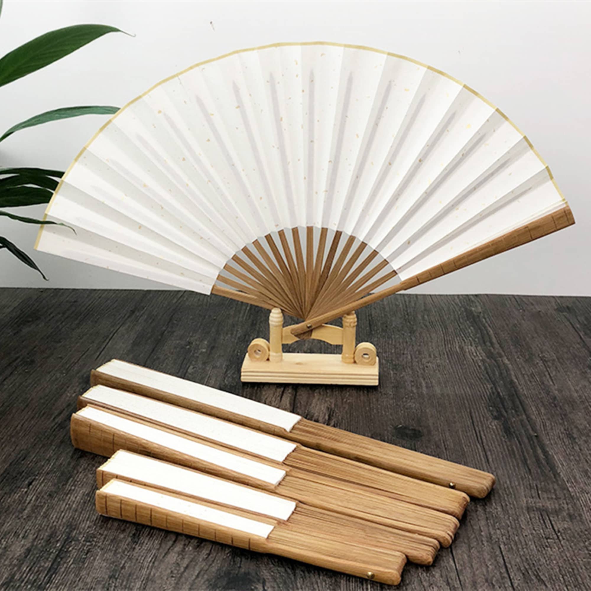 A folding fan with a wood frame and white fabric, displayed on a stand, alongside several matching wooden handles. Folding Fan - Image 1
