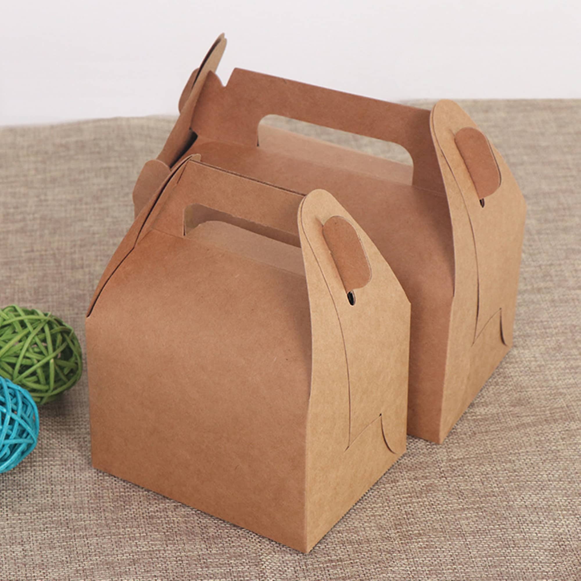 Two brown gable boxes made of kraft paper, featuring handles for easy carrying, on a textured surface. Gable Box - Image 1