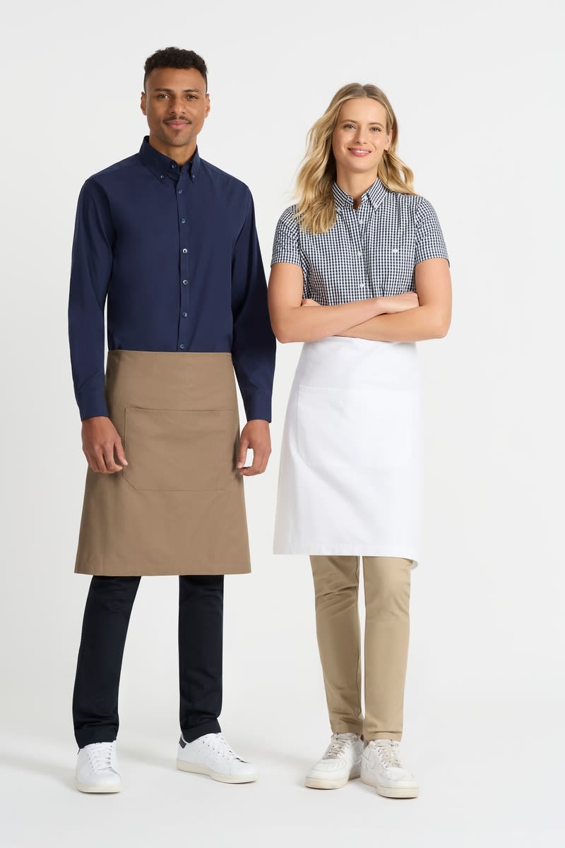 A navy blue button-up shirt and a checkered short sleeve shirt worn by two models, each in an apron. Capri - Waist Apron - Image 1