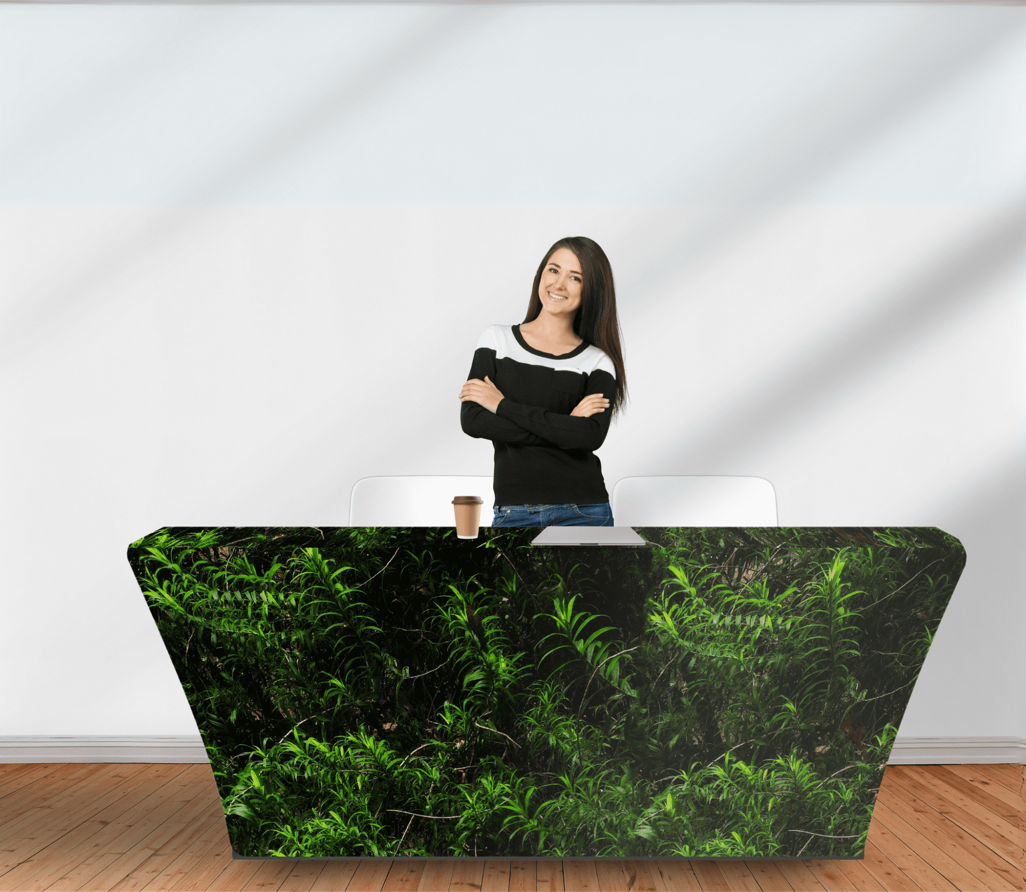 A woman stands behind a green rPET stretched table cover, featuring a leafy design, on a wooden floor. rPET Stretched Table Cover 8ft (2400mm) - Image 1