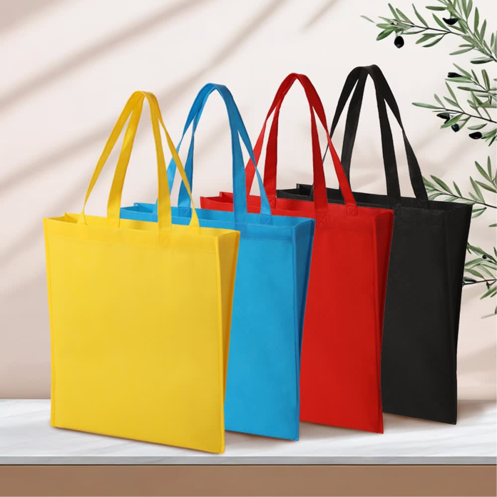 A set of four tote bags in yellow, blue, red, and black, featuring sturdy handles and a simple design. Dallas pp non woven tote bag - Image 1