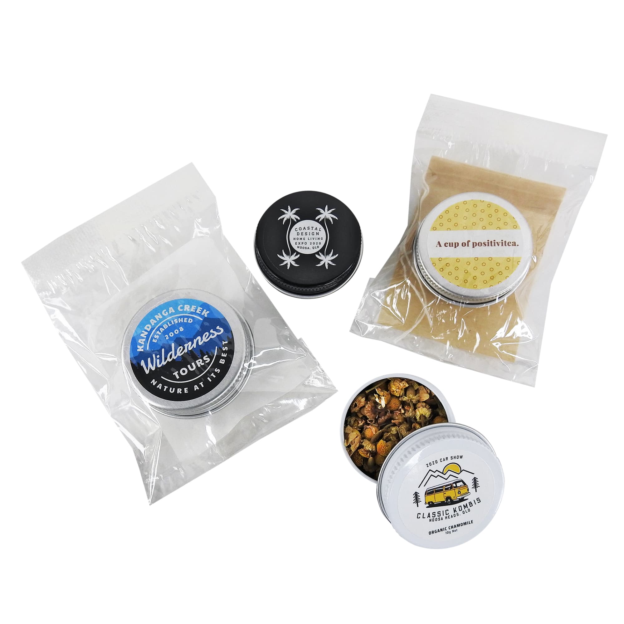 A collection of loose-leaf tea tins in black and white, alongside tea bags, enclosed in transparent packaging. Loose-Leaf Tea Twist-Top Tin - Image 1