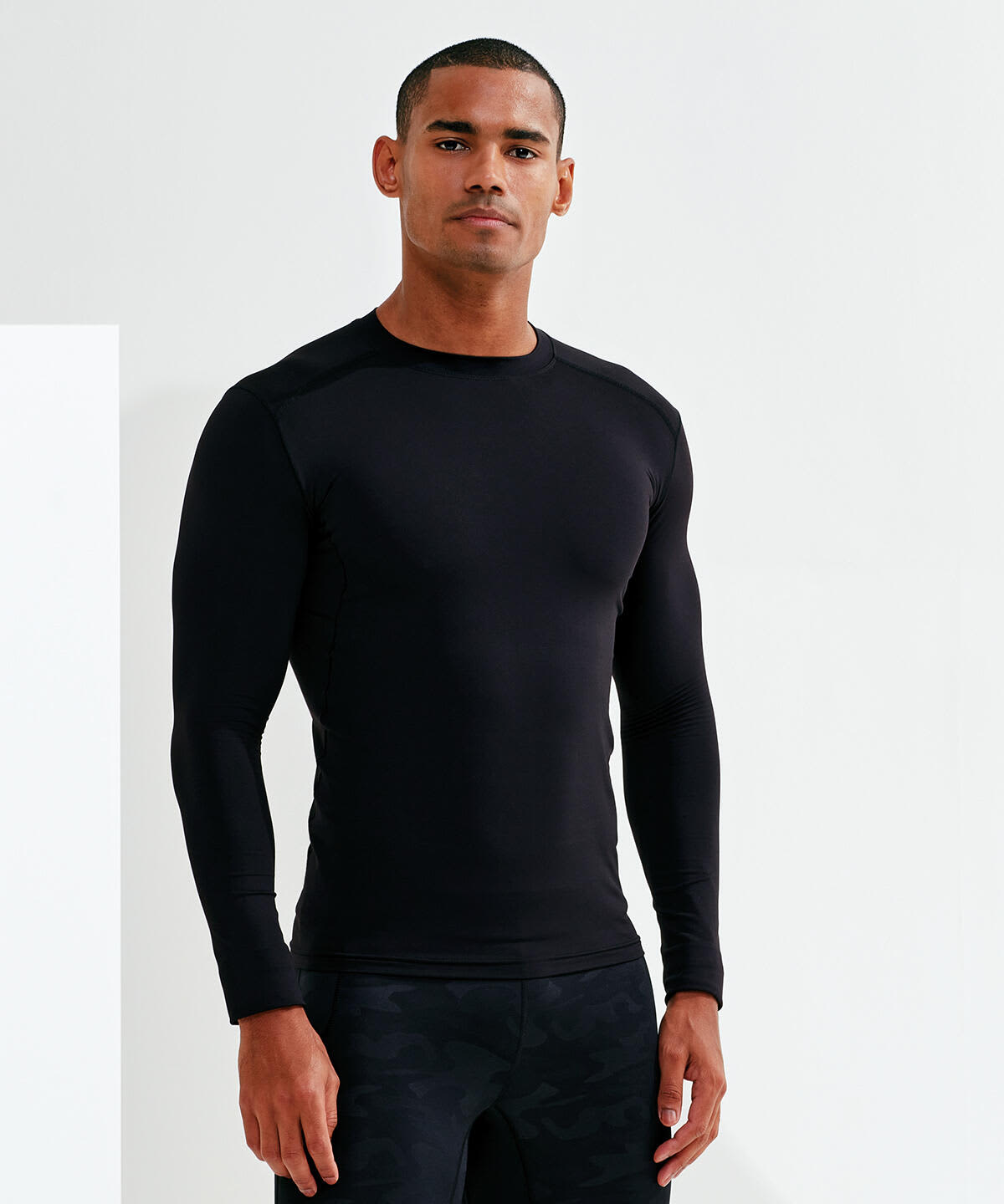 A fitted black long-sleeve top worn by a model, featuring a sleek design and a logo. Performance Baselayer - Image 1