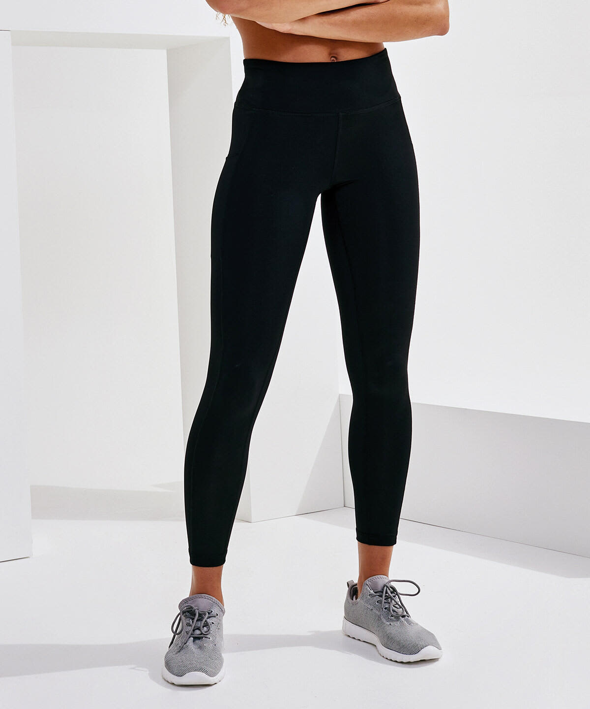 Performance leggings in black with pockets, paired with grey athletic shoes, displayed against a minimalist white background. Performance Leggings With Pockets - Image 1