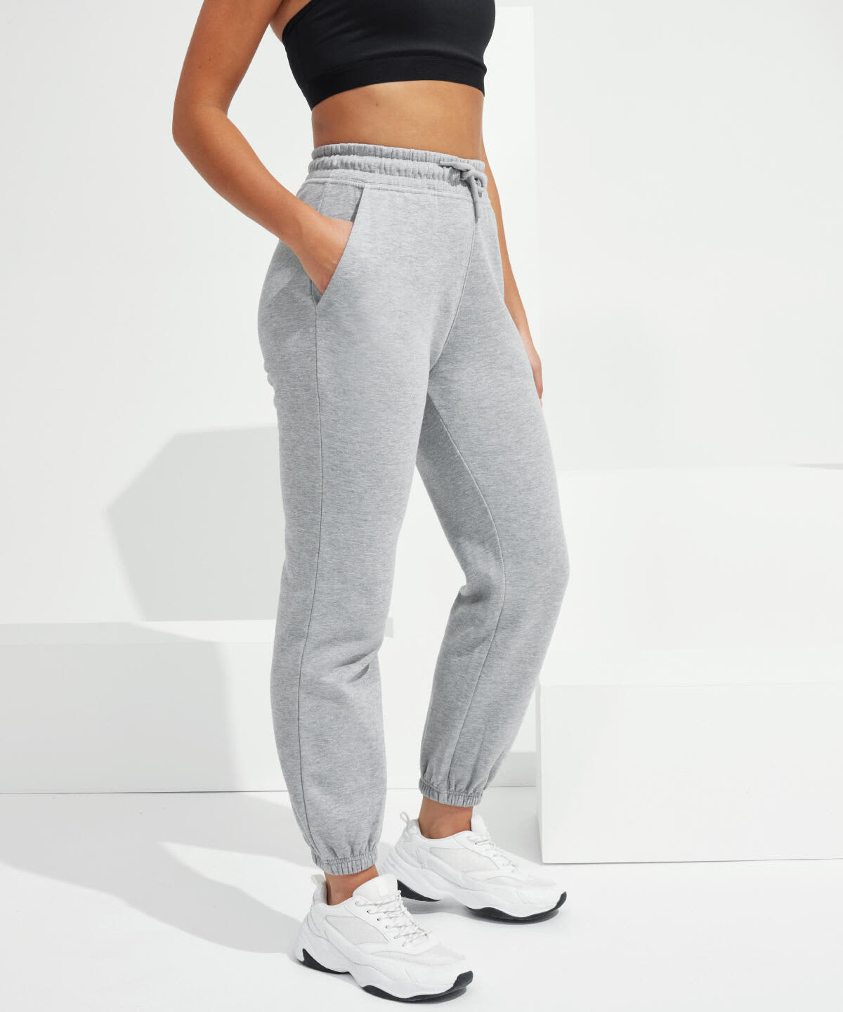 A pair of grey unisex joggers with an elastic waistband and pockets, displayed on a model. Unisex Recycled Joggers - Image 1