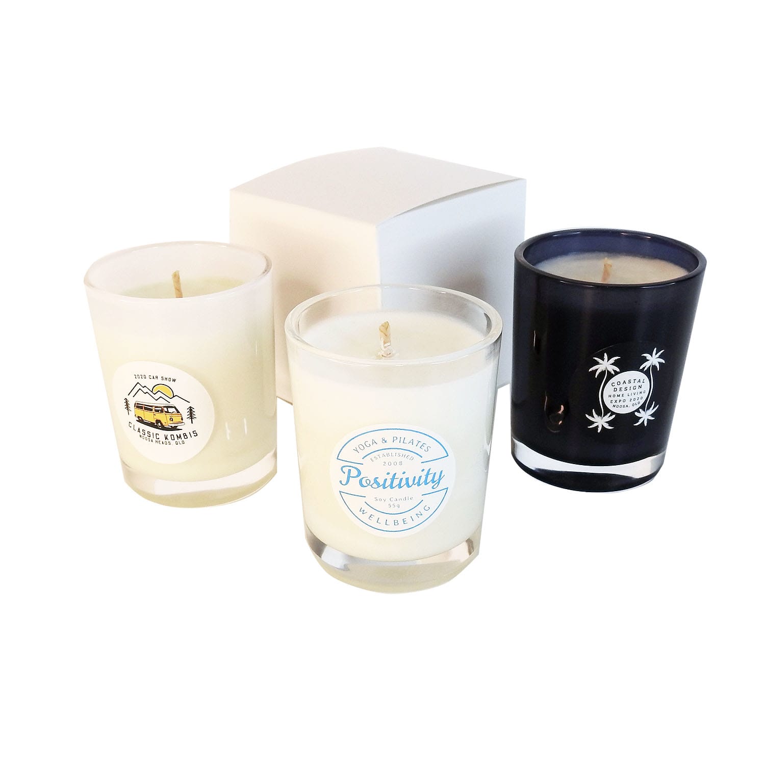Three votive glass candles in clear and black containers, featuring various designs, displayed with a white box. Votive Glass Candle - Image 1