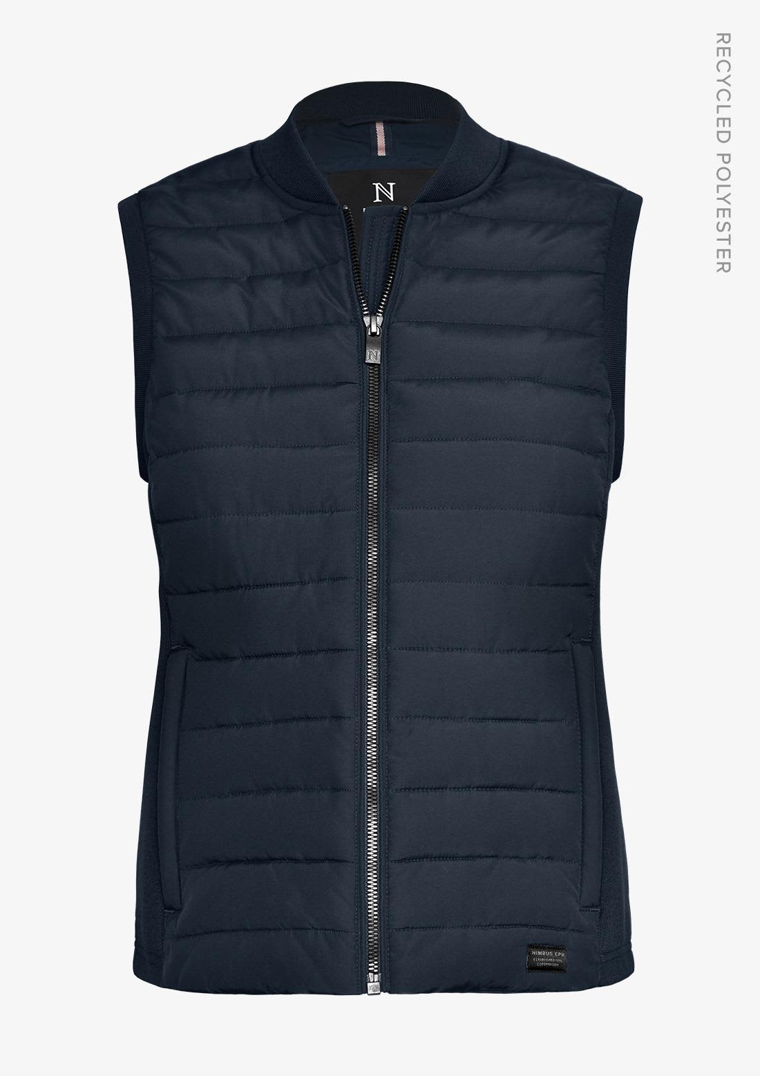 A navy women's vest featuring a zip front, padded design, and a logo on the side. Made from recycled polyester. Vesper Women Vest - Image 1