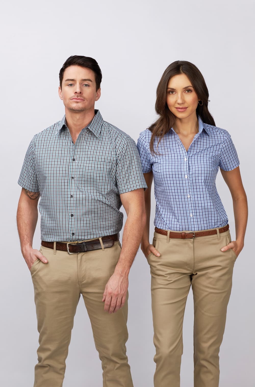 A short sleeve button-up shirt in blue and white check pattern worn by a man and woman, paired with beige trousers. Hudson - Mens Short Sleeve Shirt - Image 1