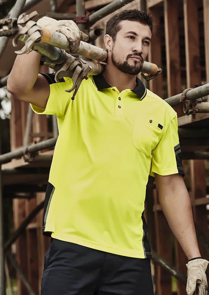 A man in a bright yellow short sleeve polo with black accents, carrying scaffolding pipes at a construction site. Mens Hi Vis Reinforced Squad Short Sleeve Polo - Image 1