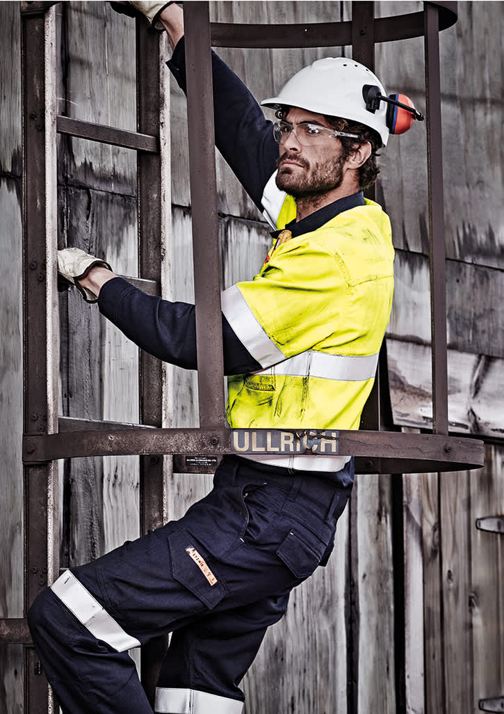 A man wearing a hi-vis yellow and navy work shirt, climbing a metal ladder, with protective gear and glasses. Mens Orange Flame Hi Vis Closed Front Shirt - Hoop Taped - Image 1