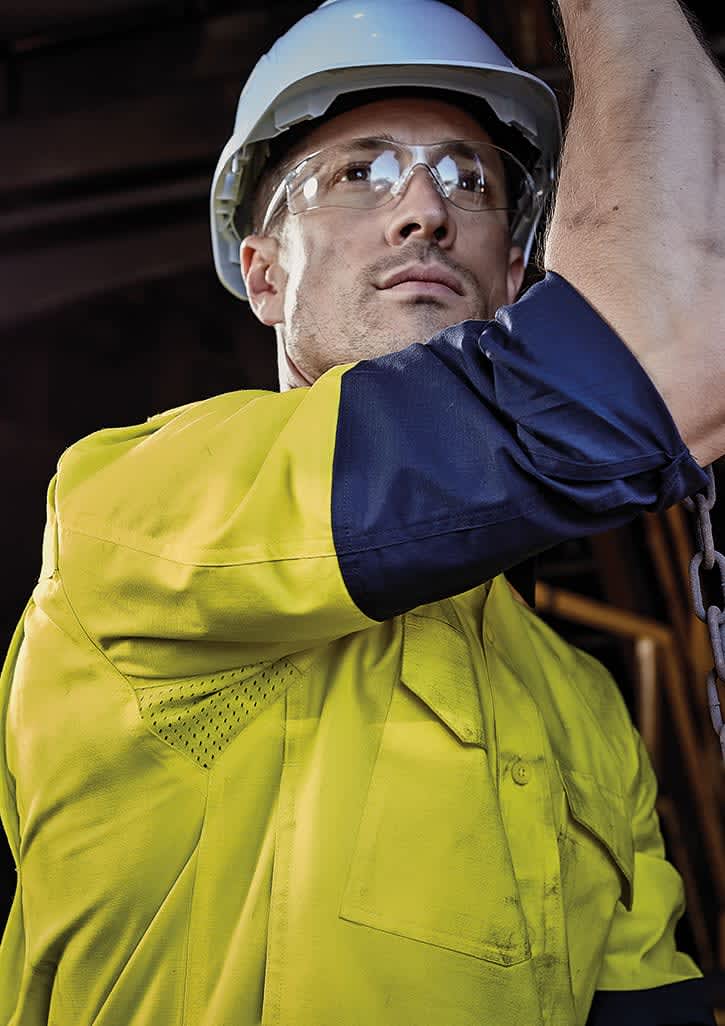 A men’s closed front long sleeve shirt in yellow and navy, featuring a logo, worn with safety goggles and a hard hat. Mens Closed Front Long Sleeve Shirt - Image 1