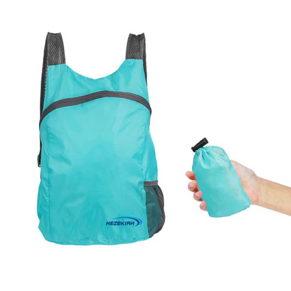 A light blue foldable backpack beside a hand holding it in a compact form. The backpack features a logo. Promotional Lightweight Foldable Backpack - Image 1