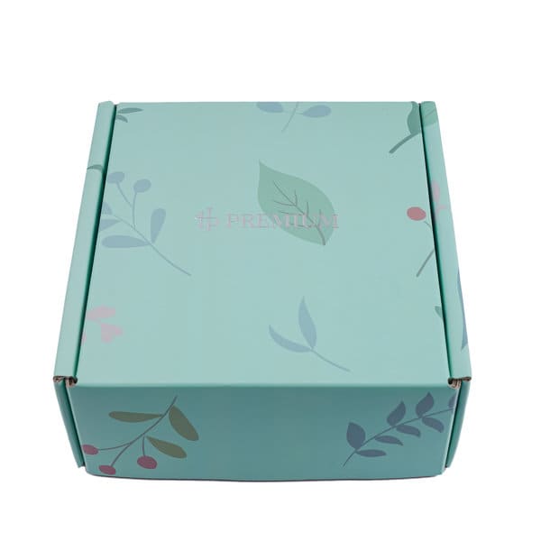 A teal packaging box with floral designs in pink and green. It has a logo on the surface. Small Custom Shipping Packaging Box - Image 1