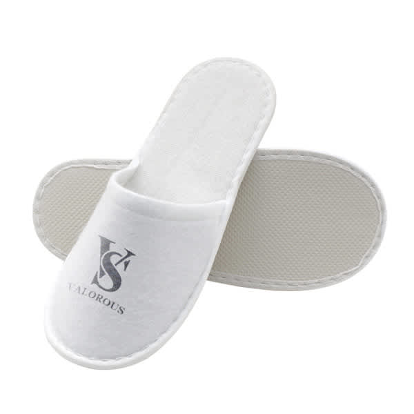 White disposable hotel slippers with a textured sole and a logo printed on the upper. Disposable Hotel Slippers - Image 1