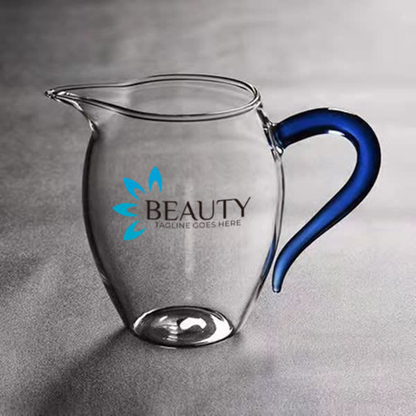 A drink jug made of clear borosilicate glass with a blue handle and featuring a logo. 12 oz. Borosilicate Glass Tea Fairness Cup - Image 1