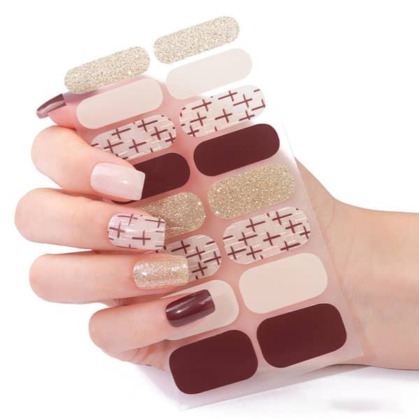 A hand holding a sheet of custom nail art stickers in shades of nude, burgundy, and glittery gold. Custom Nail Art Stickers - Image 1