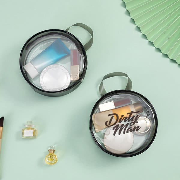 Two clear PVC round cosmetic bags in black, containing various toiletry items, with small handles for easy carrying. Clear PVC Round Cosmetic Bag - Image 1