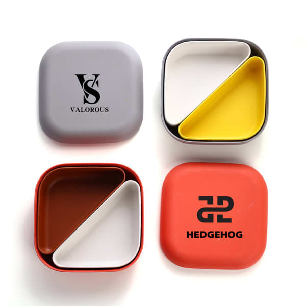 A set of four bento lunch boxes in grey, yellow, brown, and red, featuring logos on two of the boxes. Kids Bento Lunch Box - Image 1