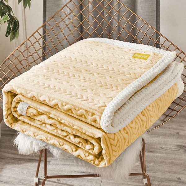 A folded winter quilt cover in soft yellow with a textured pattern and white trim, resting on a chair. Winter Quilt Cover - Image 1