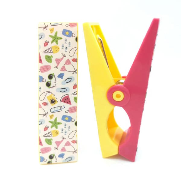 A pink and yellow windproof cloth clip next to a patterned card featuring various beach-themed illustrations. Personalized Cute Windproof Cloth Clip - Image 1