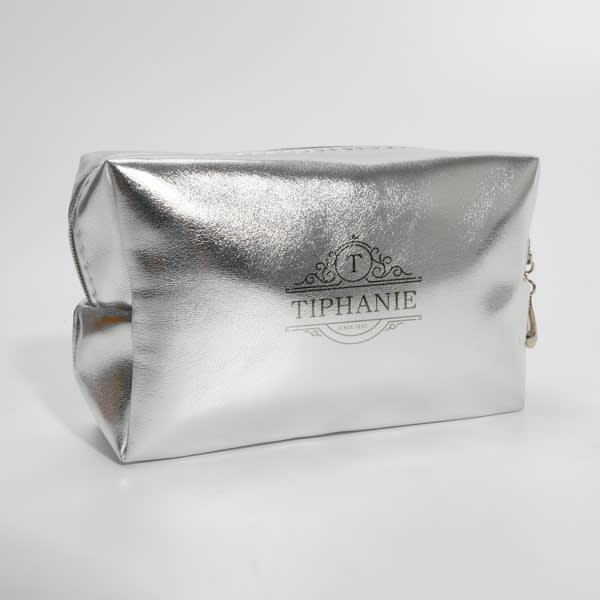 A shiny silver PU leather cosmetic bag featuring a logo on the front. The bag has a rectangular shape. Square PU Leather Cosmetic Bag - Image 1