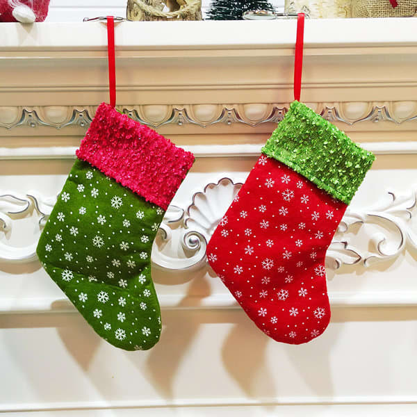 Two Christmas stocking-shaped gift bags in green and red, adorned with white snowflakes and bright fabric tops. Christmas Stocking Shaped Gift Bag - Image 1