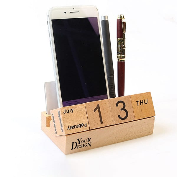 A wooden perpetual calendar featuring a pen holder and space for a smartphone, with a natural finish. Wooden Blocks Perpetual Calendar With Pen Holder - Image 1