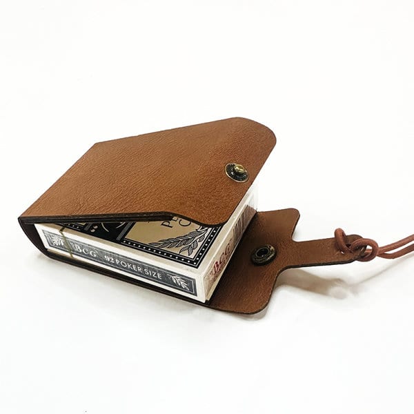 A brown leather travel cribbage board with a button closure, holding a deck of playing cards inside. Leather Travel Cribbage Board - Image 1