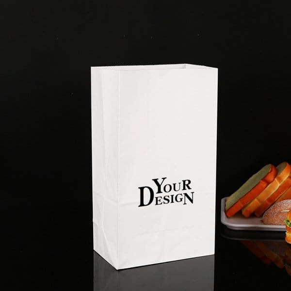 A white oil-proof food packaging bag stands upright, featuring a logo and displaying sandwiches on a tray beside it. Custom Oil Proof Food Packaging Bag - Image 1