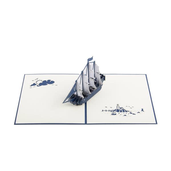 A 3D pop-up greeting card featuring a detailed sailing boat in navy blue atop a cream background with decorative elements. Creative 3D Sailing Boat Greeting Card - Image 1
